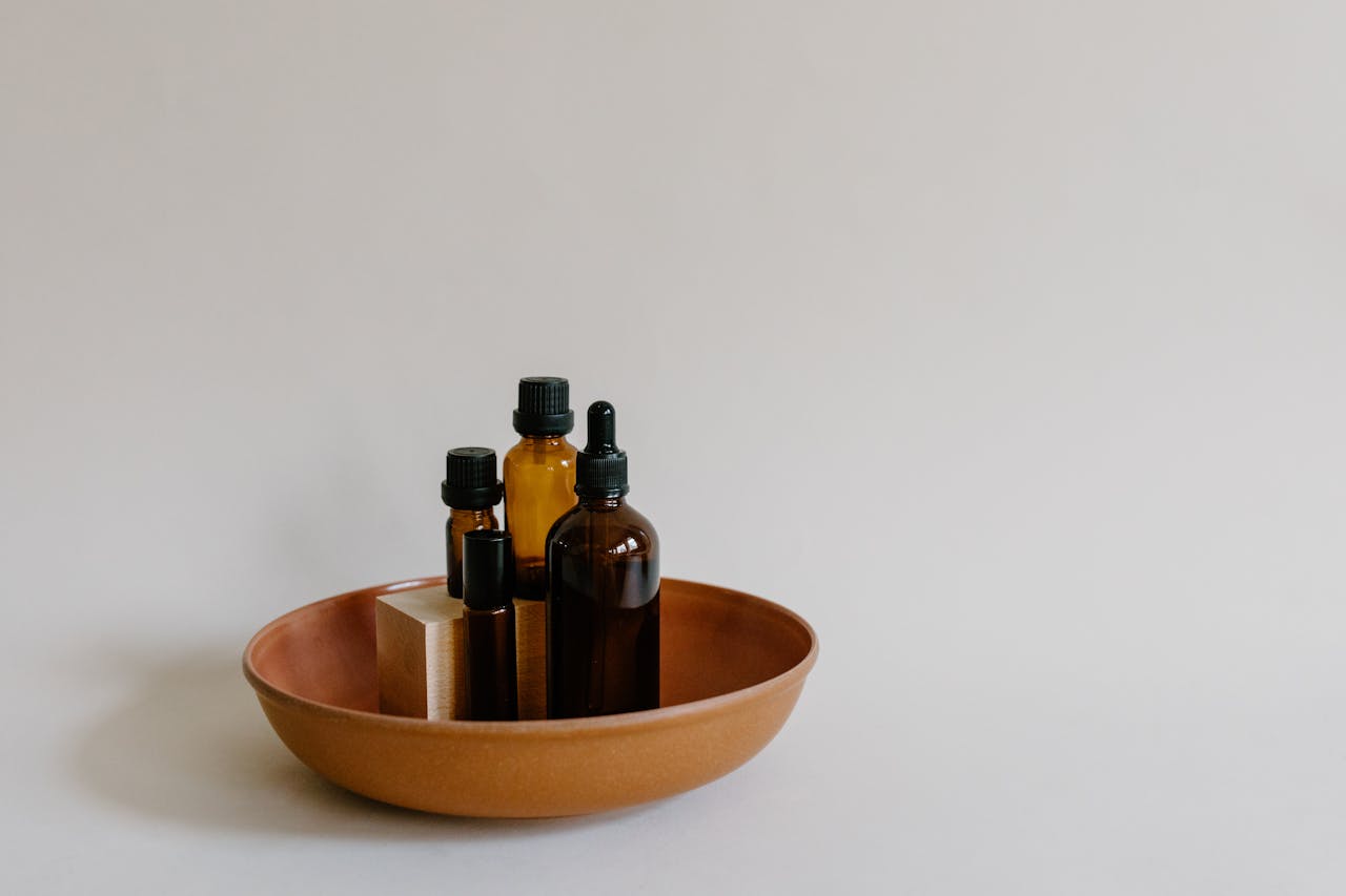 services-10 Elegant still life image of essential oil bottles in a brown dish on a neutral background.