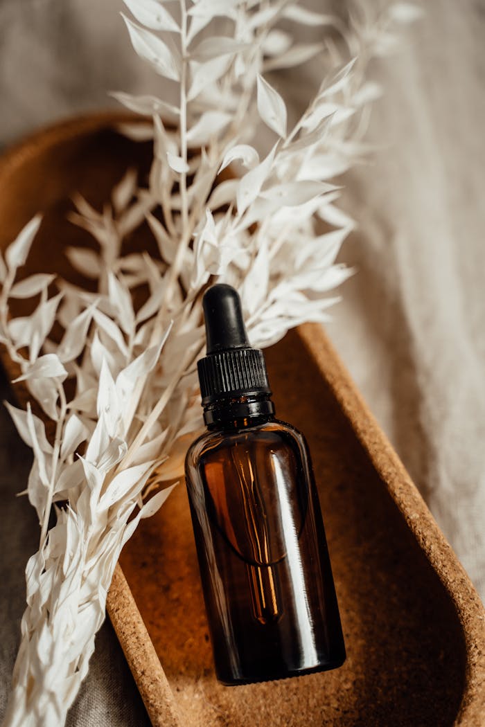 portfolio-01 Aesthetic shot of a brown glass dropper bottle with dried leaves in warm tones.